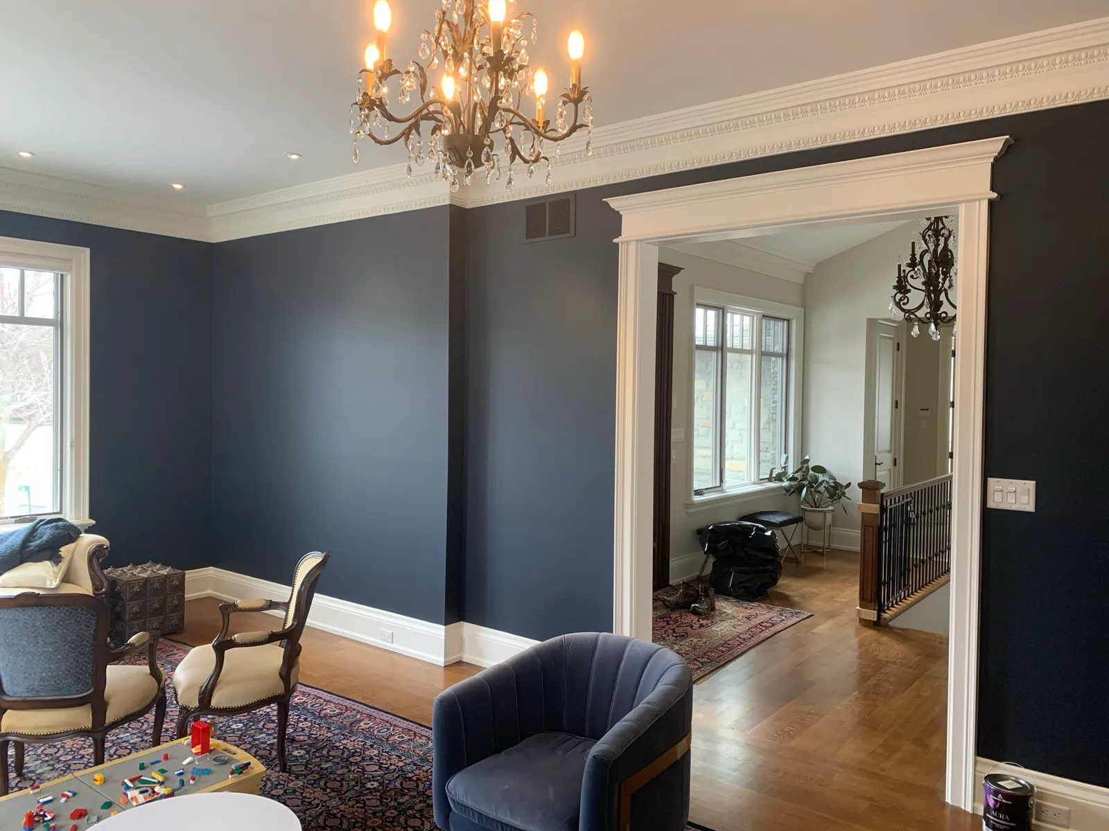 The same living room after painting, the walls a deep navy that sets off the white trim and archway.