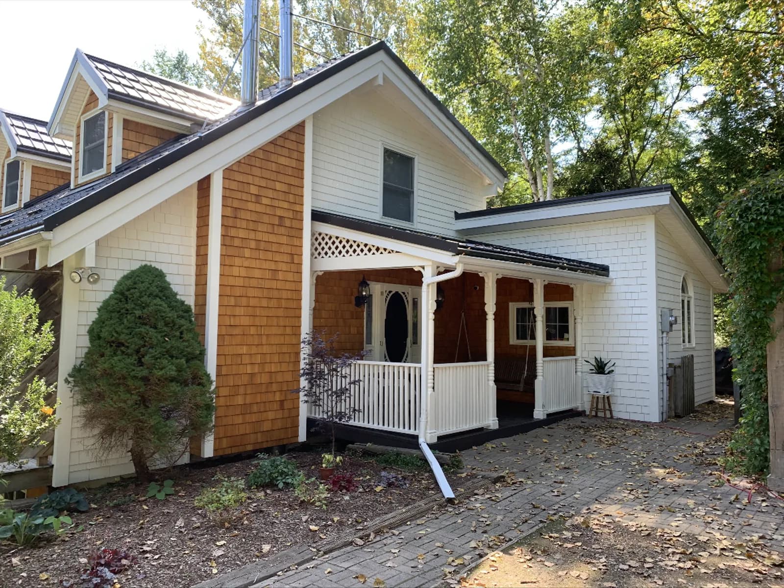 The same cottage after painting, the body crisp white with a natural cedar shake gable left as an accent.