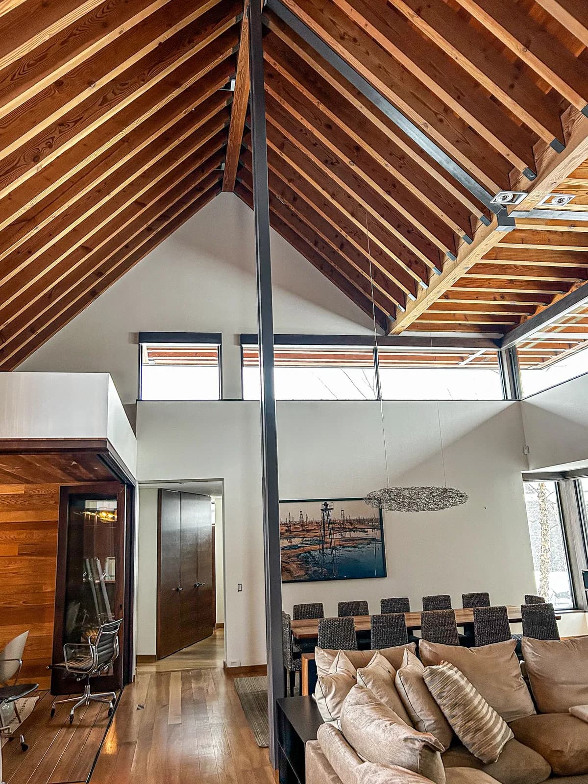 A Clarksburg interior with exposed timber rafters over a vaulted ceiling, white painted walls and clerestory windows above the dining area.