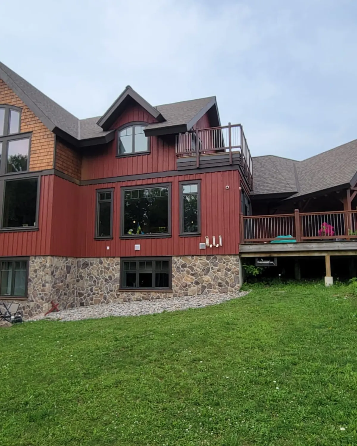 A timber frame home near Markdale finished in deep barn red above stone footings and a wide covered deck.
