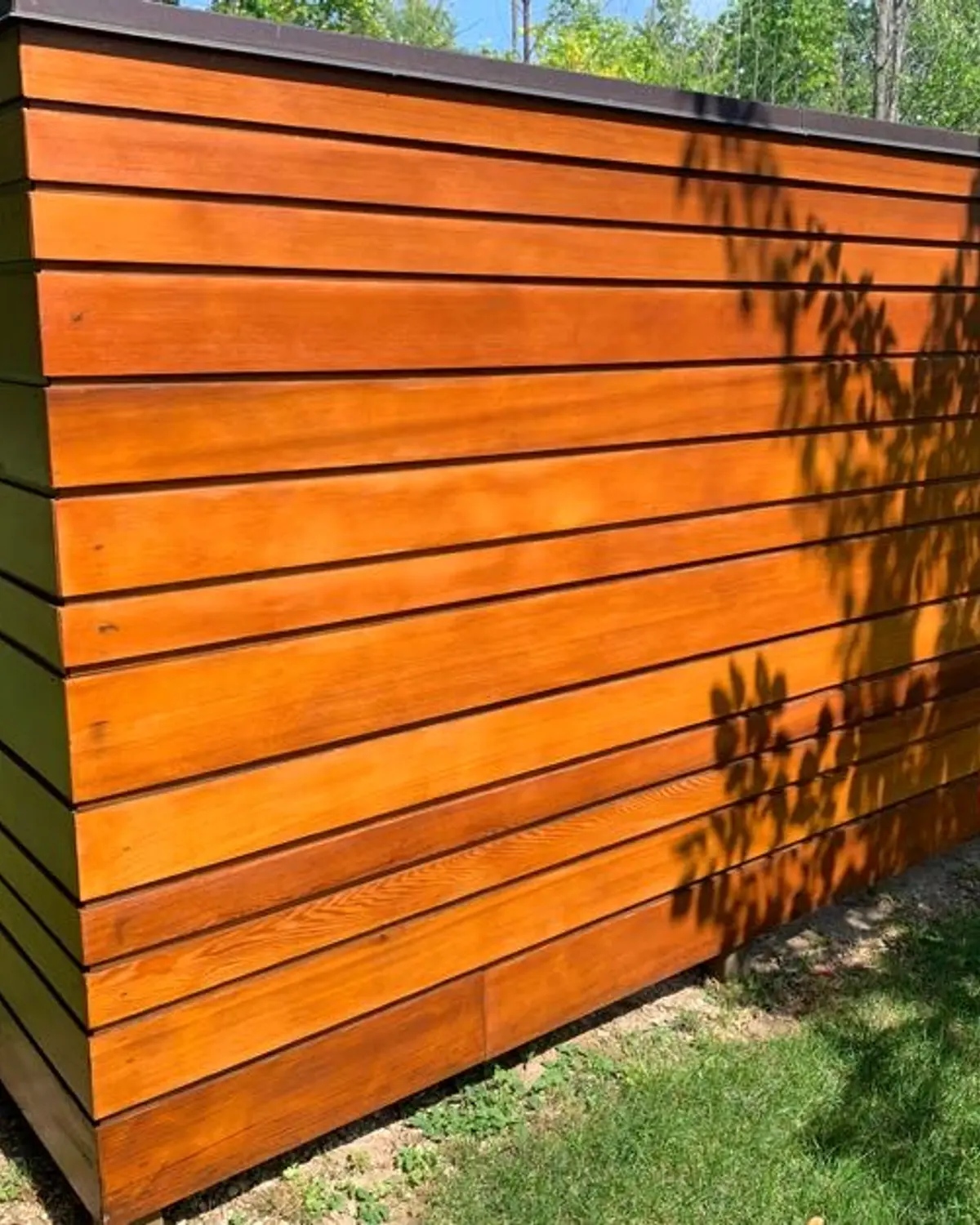 A wall of horizontal cedar cladding in Blue Mountain, freshly stained a warm orange brown.