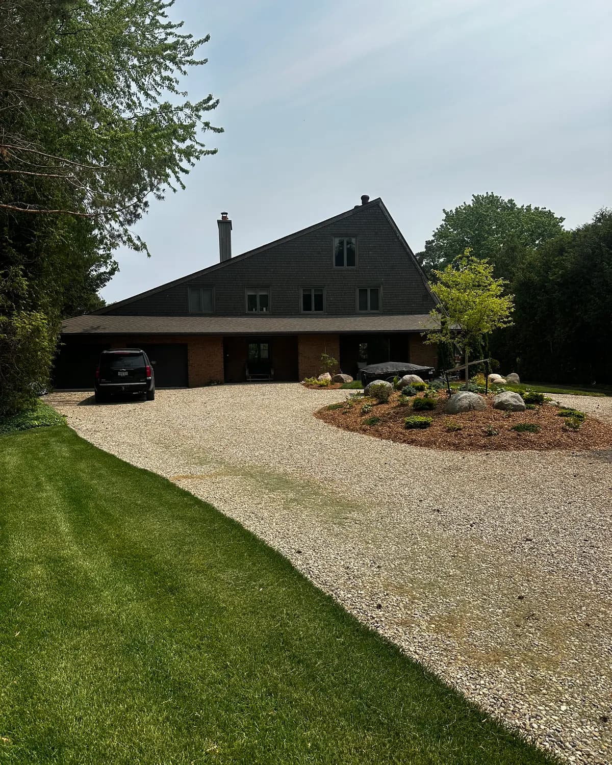A Collingwood home seen down its gravel drive after a full exterior repaint in deep brown.