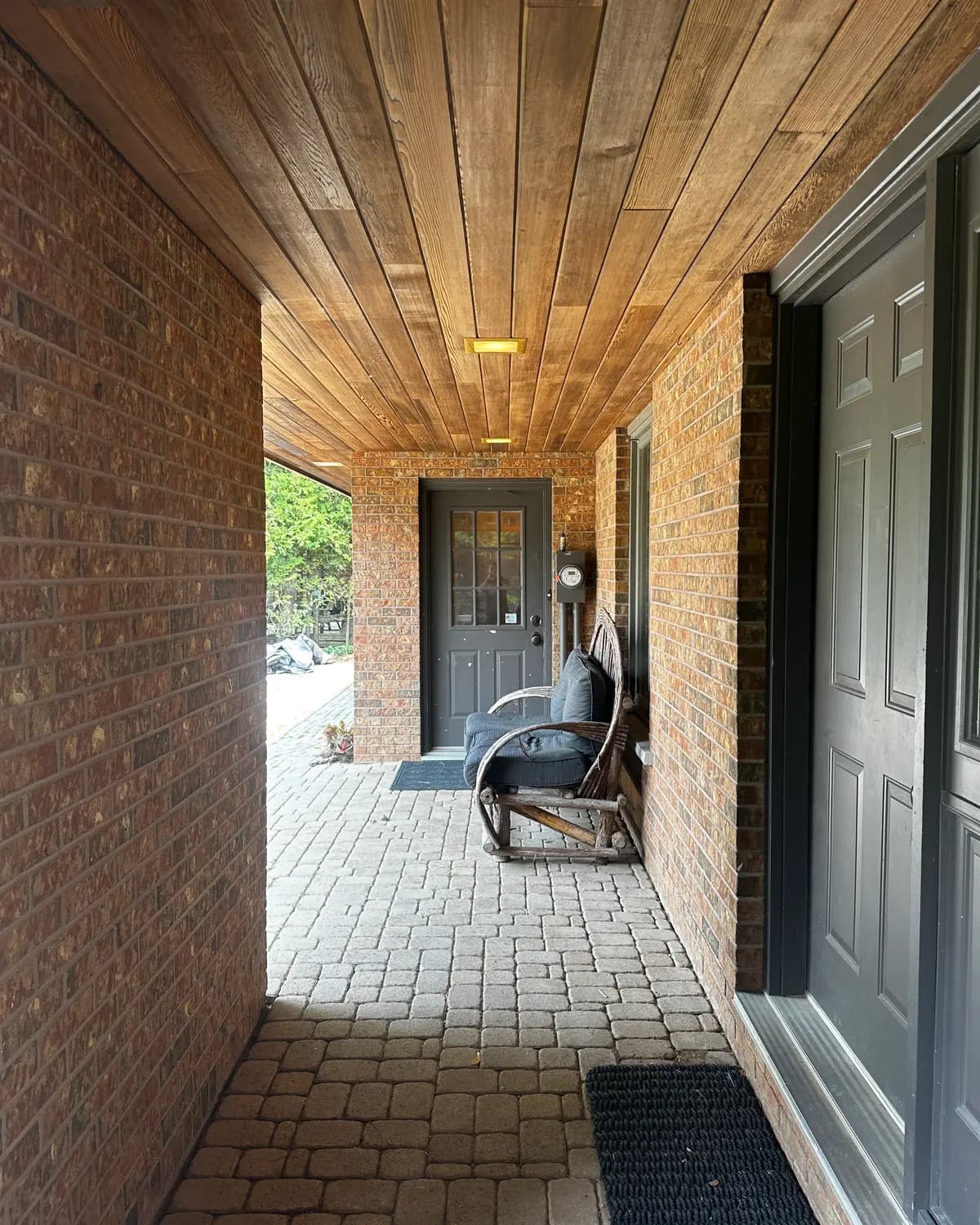 A covered entry in Collingwood with a stained wood ceiling above a freshly painted black door.