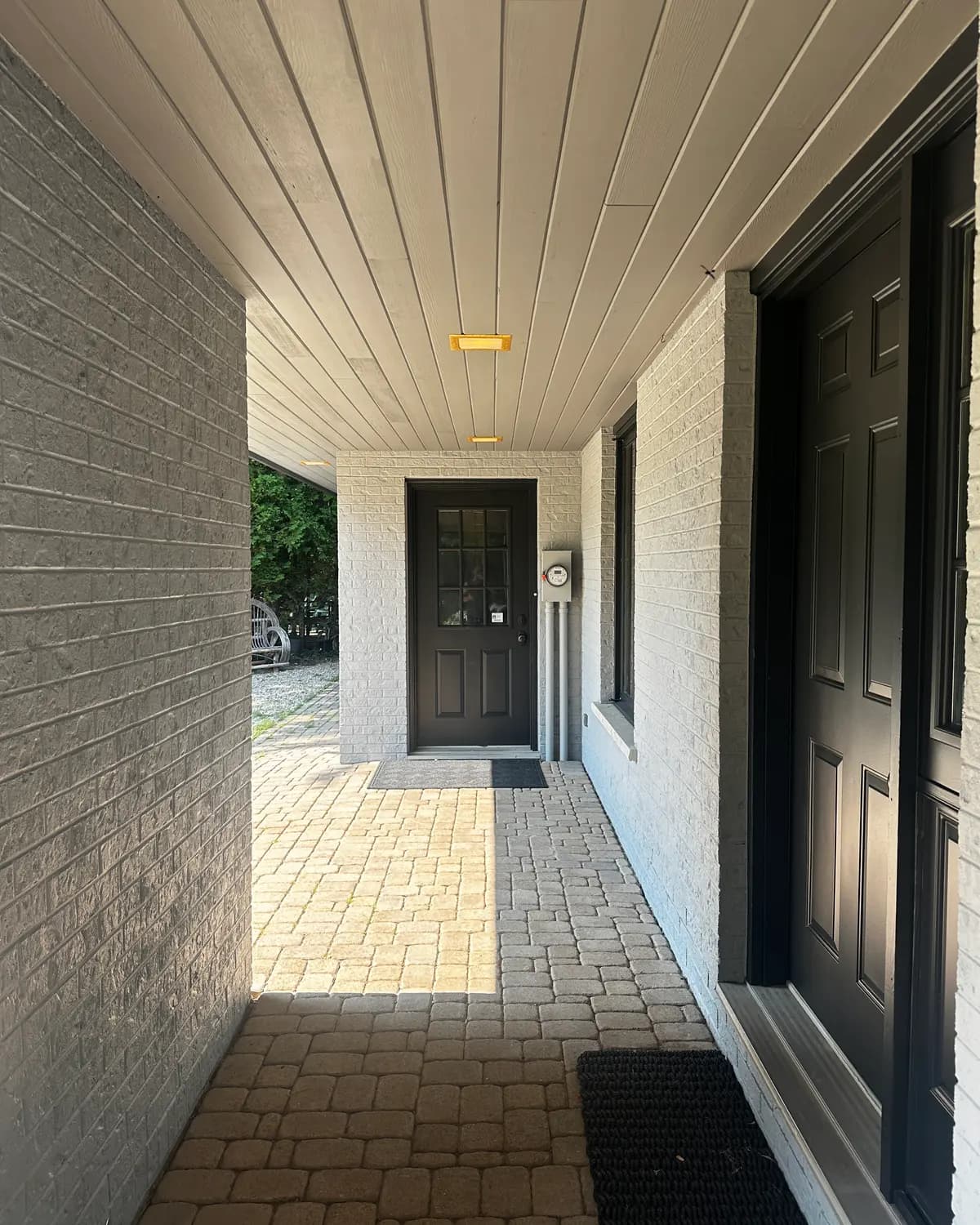 The front entry of a Collingwood home, its door and surround painted black against pale stone and brick.