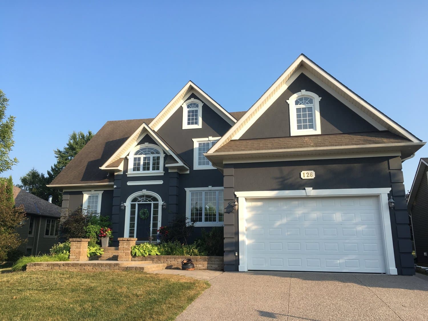 Navy blue home exterior with crisp white trim glowing in evening light after a full repaint.