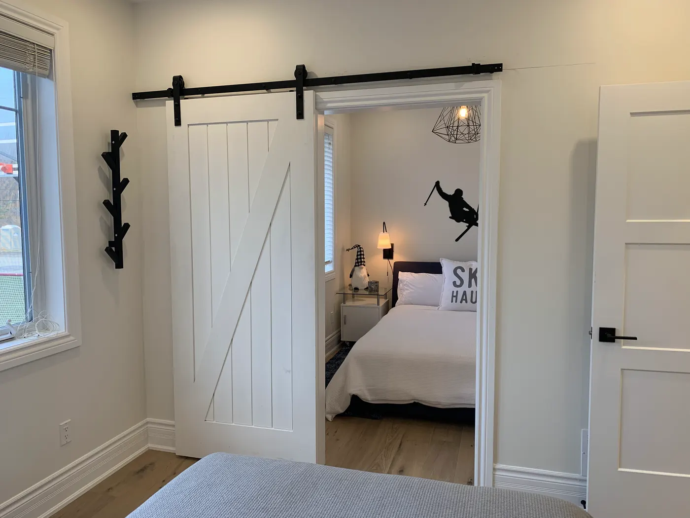 A sliding barn door painted white on black hardware, opening from a landing into a bedroom.