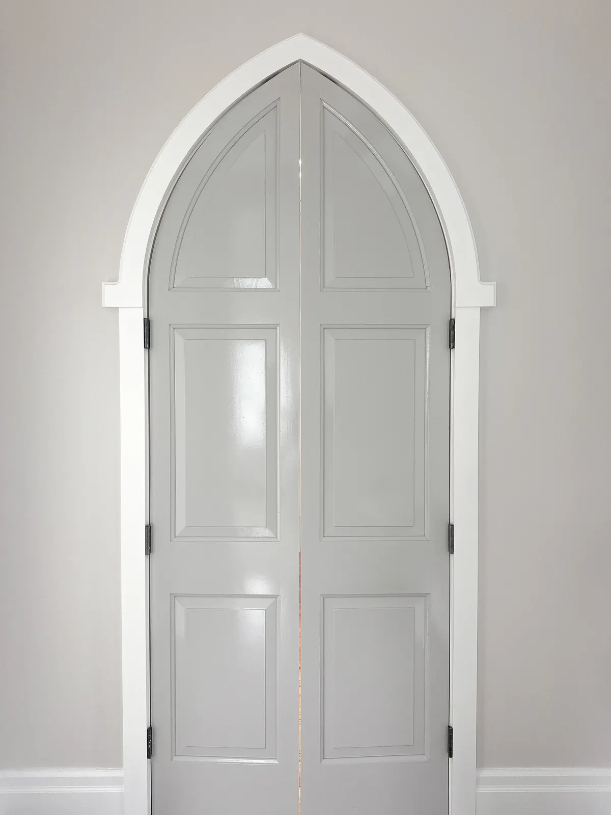 Tall arched double doors freshly painted in a Snowbridge chalet, set into a plastered archway.