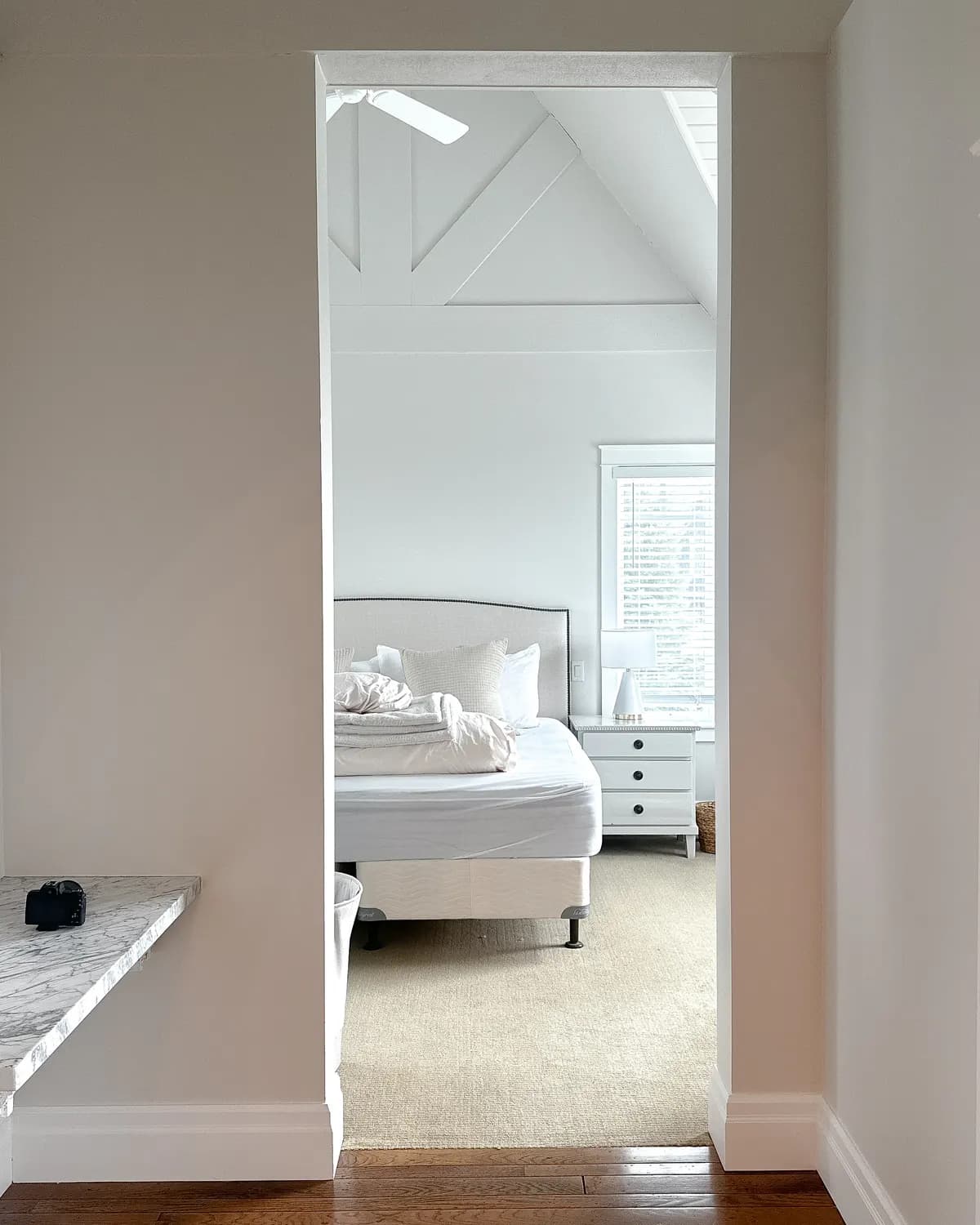 A bedroom seen through a painted doorway in a Snowbridge chalet, under a vaulted white ceiling.