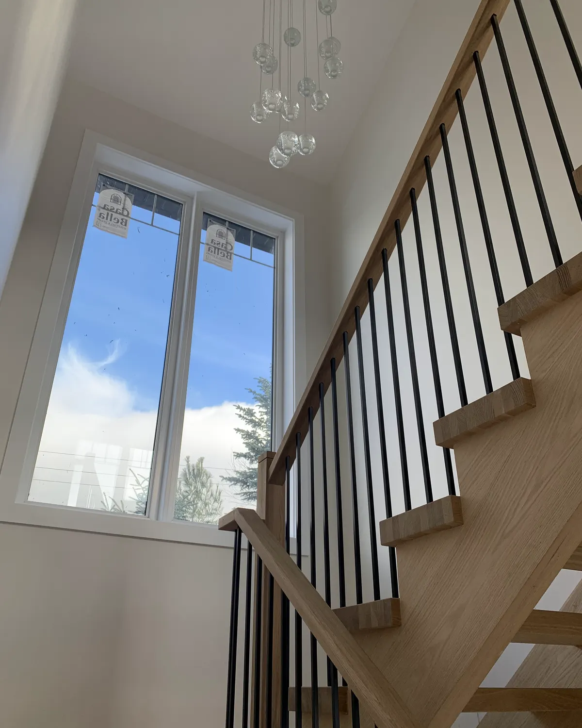 A painted stairwell in a Blue Mountain chalet with a tall window, timber handrail and black spindles.
