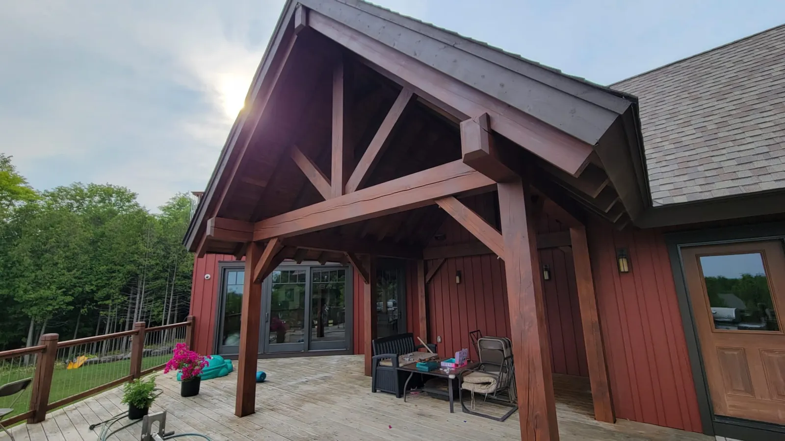 The covered timber entry of a home near Markdale, its heavy beams sanded back and restained in transparent stain above a stone patio.