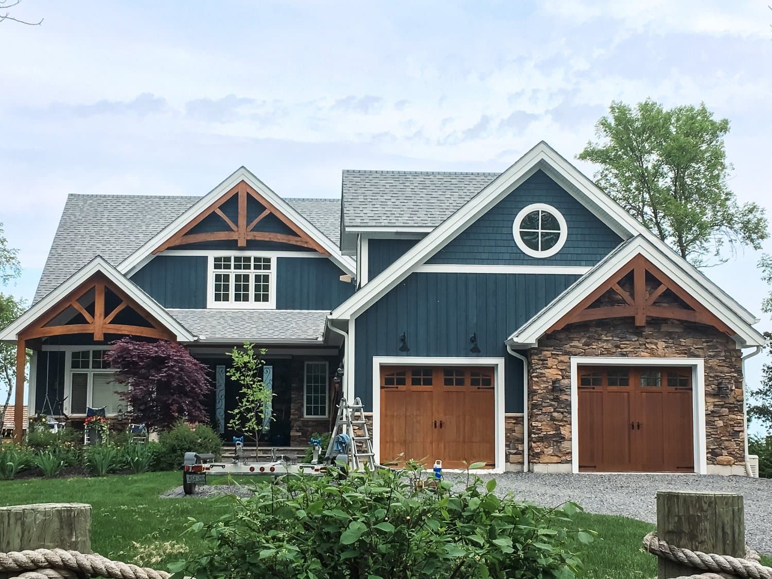 Craftsman home painted navy blue with stained cedar gable brackets and carriage style garage doors during a MountainWood project.