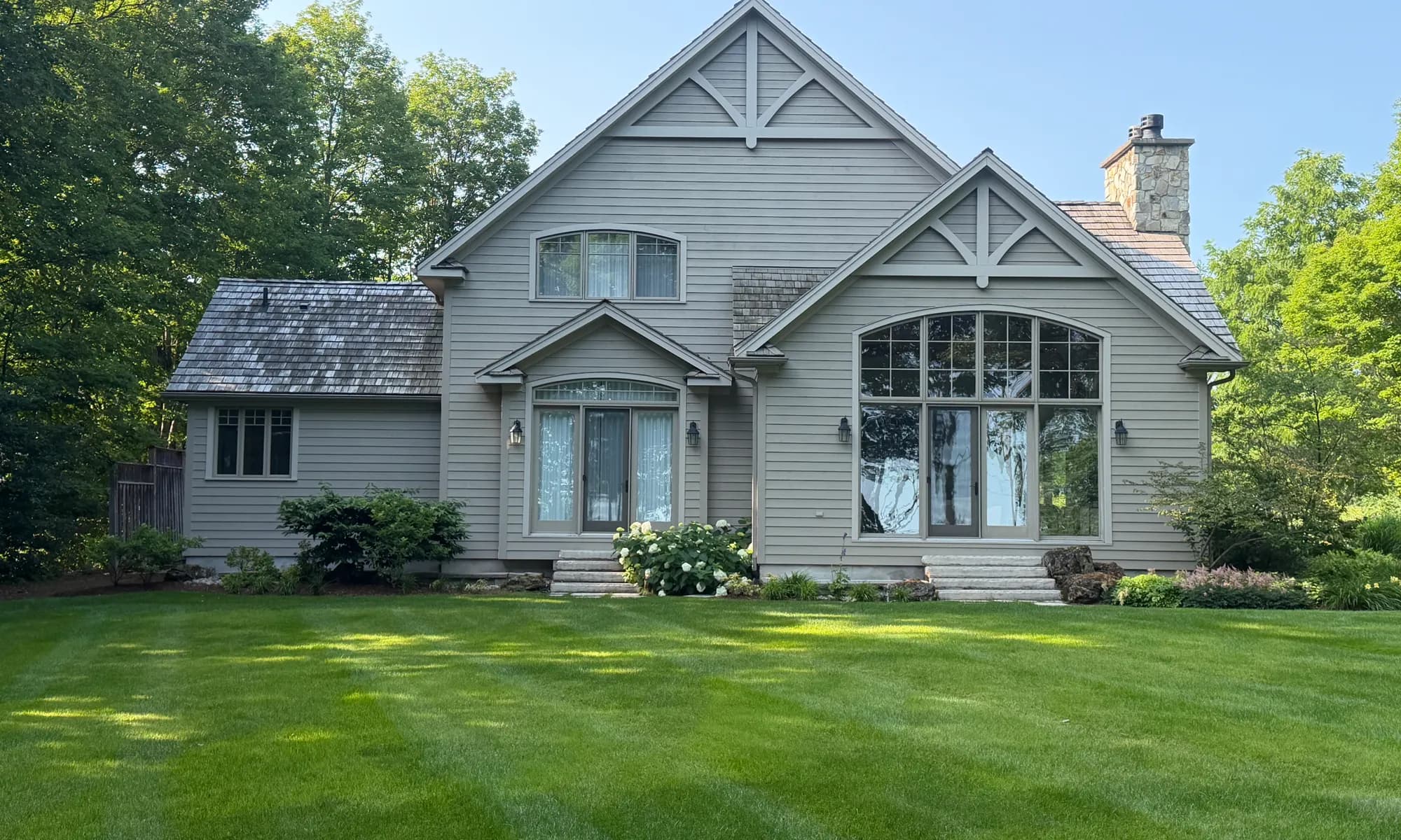 A large Craigleith home after a full exterior repaint, its siding, trim and gables finished in soft grey above a mown lawn.