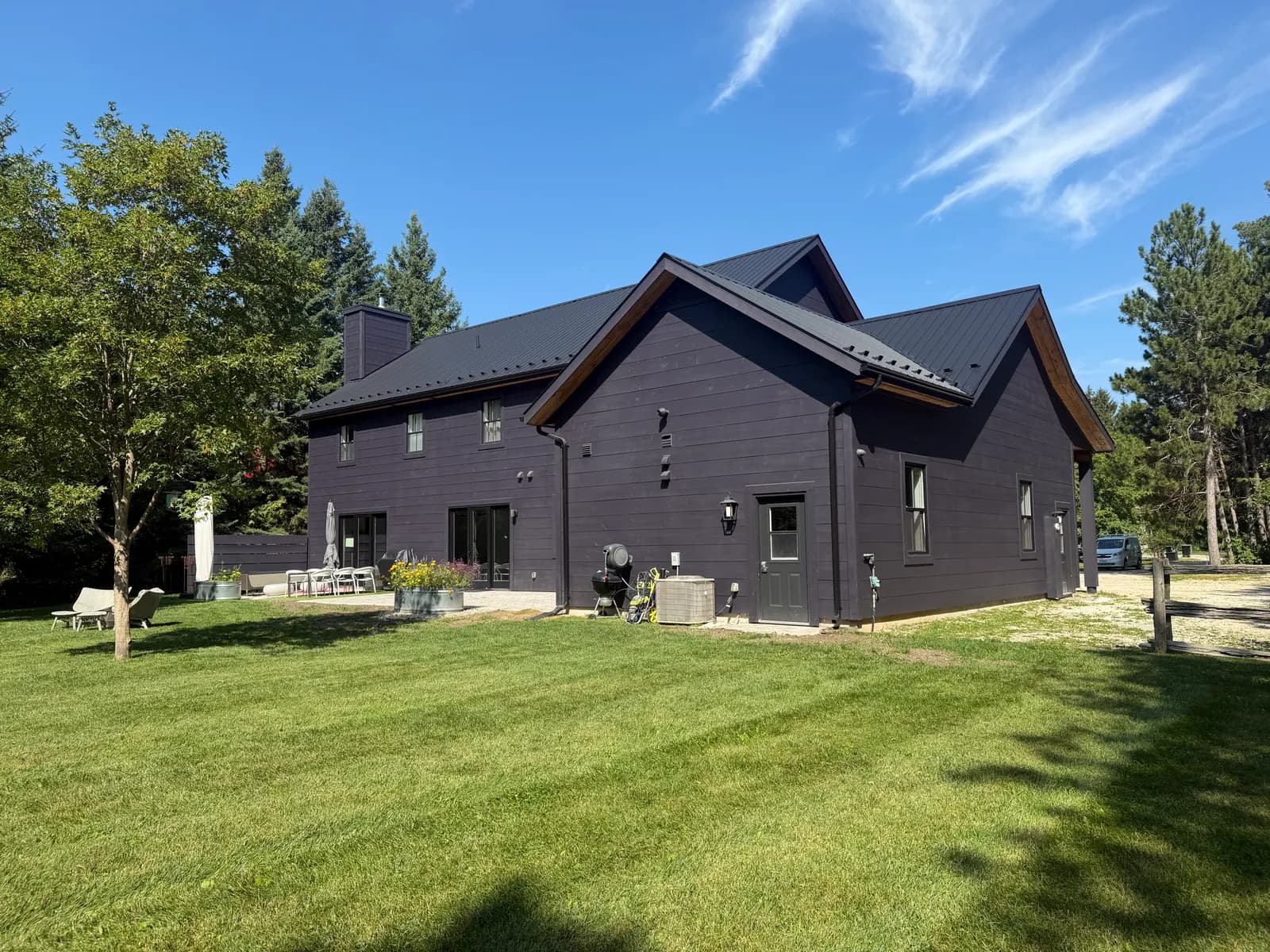 A Nottawa country home stained in Benjamin Moore Galaxy, a deep purple that reads almost black against the summer grass.