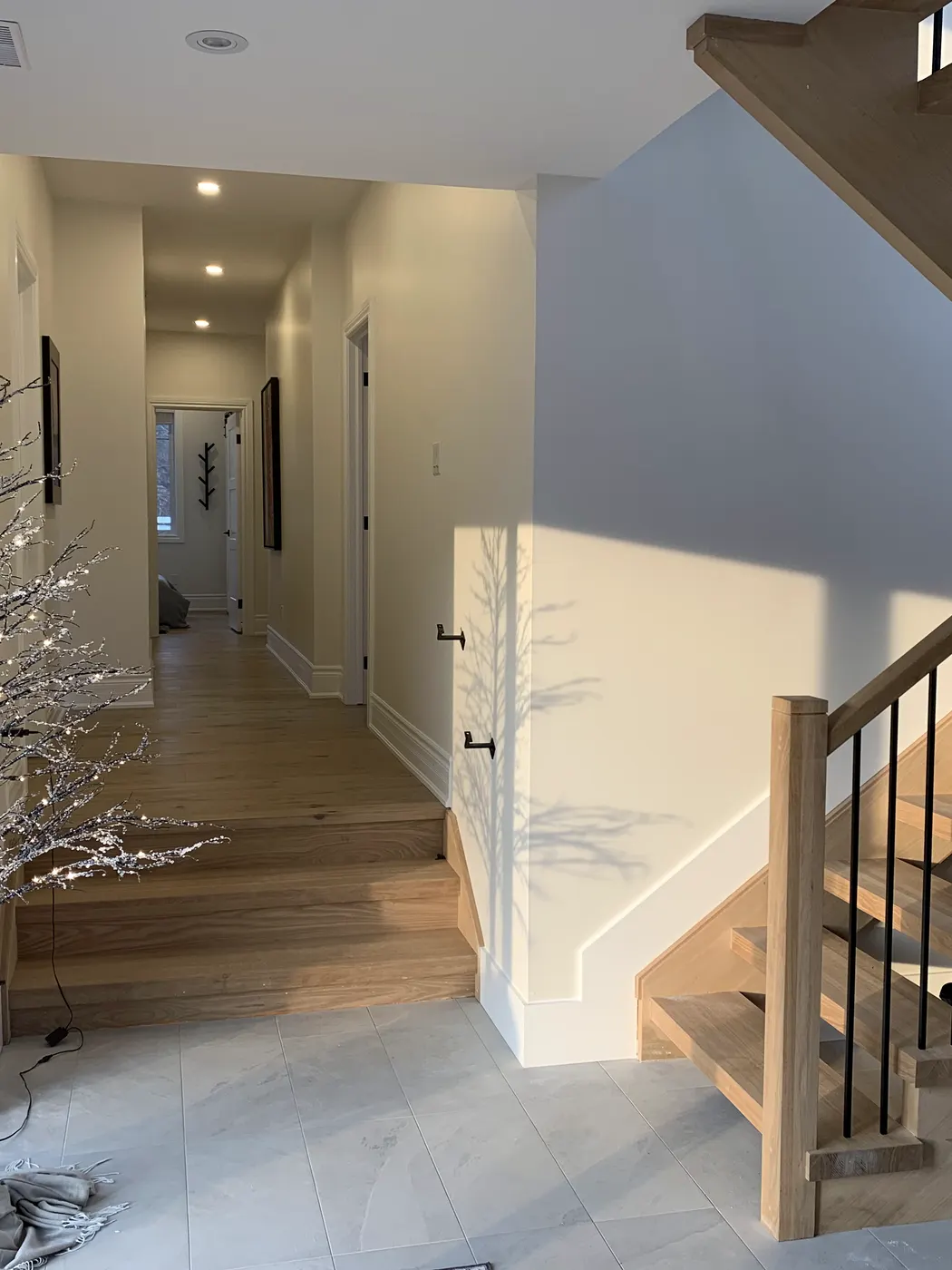 A freshly painted hallway leading to a staircase with a black metal railing and wide plank floors.